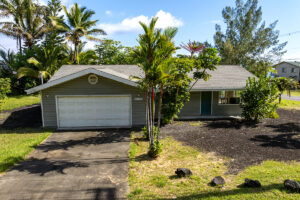 Single-story house with garage and tropical plants.